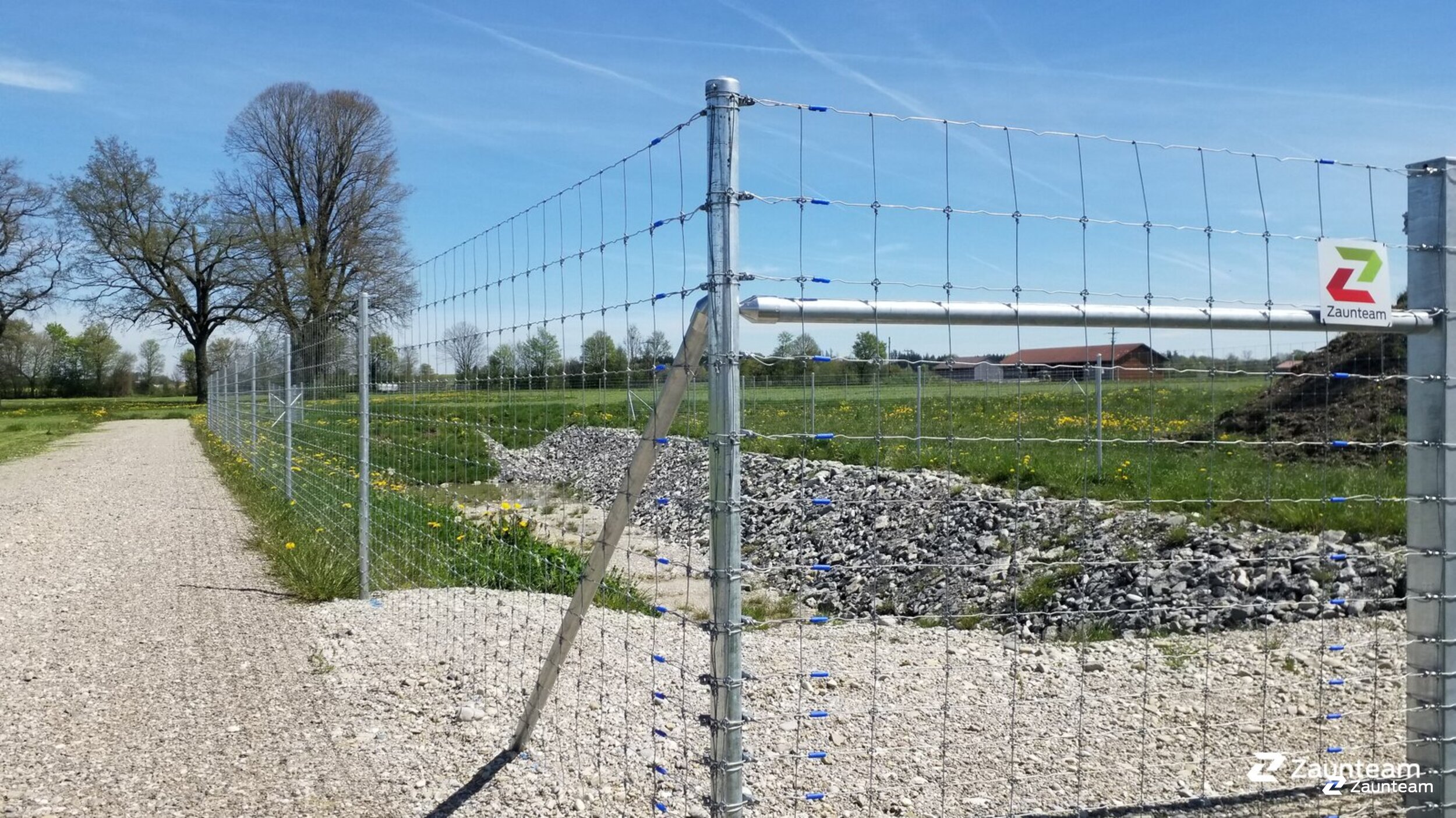 Ein malerisches Bild eines zeitlosen Knotengitterzauns, der sanft die Weiden durchzieht und als zuverlässige Barriere für majestätische Hirsche dient. Die Patina der Zeit schenkt diesem Zaun Charakter, während er behutsam die Grenzen zwischen Mensch und Natur definiert. Ein Symbol für nachhaltige Tierhaltung und harmonisches Miteinander von Tieren und Umgebung. | © Zaunteam